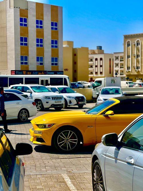 Free Bright yellow sports car parked in Dubai urban parking lot on a sunny day. Stock Photo