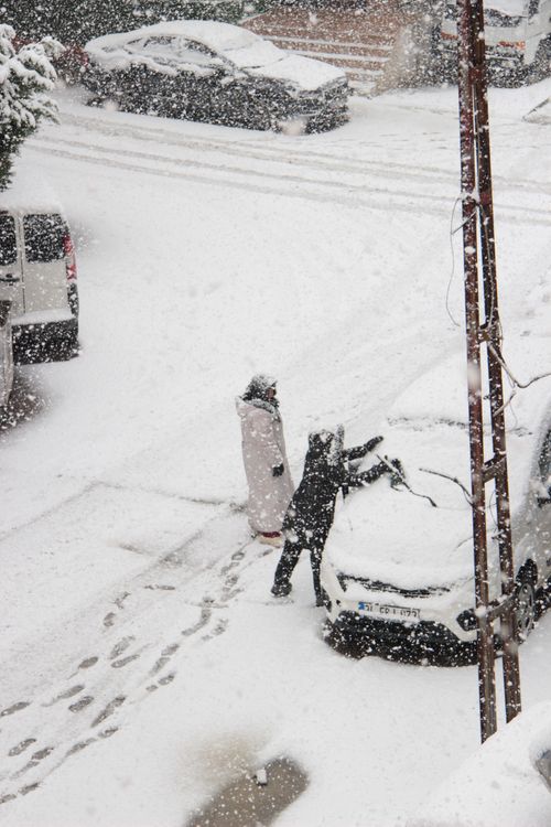 Free People cleaning snow off cars during heavy snowfall in a city street. Stock Photo