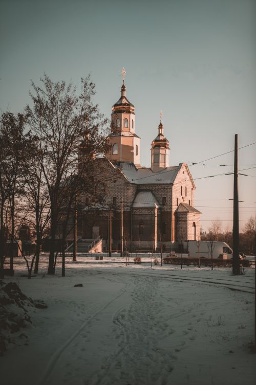Free A serene scene of a historic church in a snowy landscape during sunset, offering a peaceful winter ambiance. Stock Photo