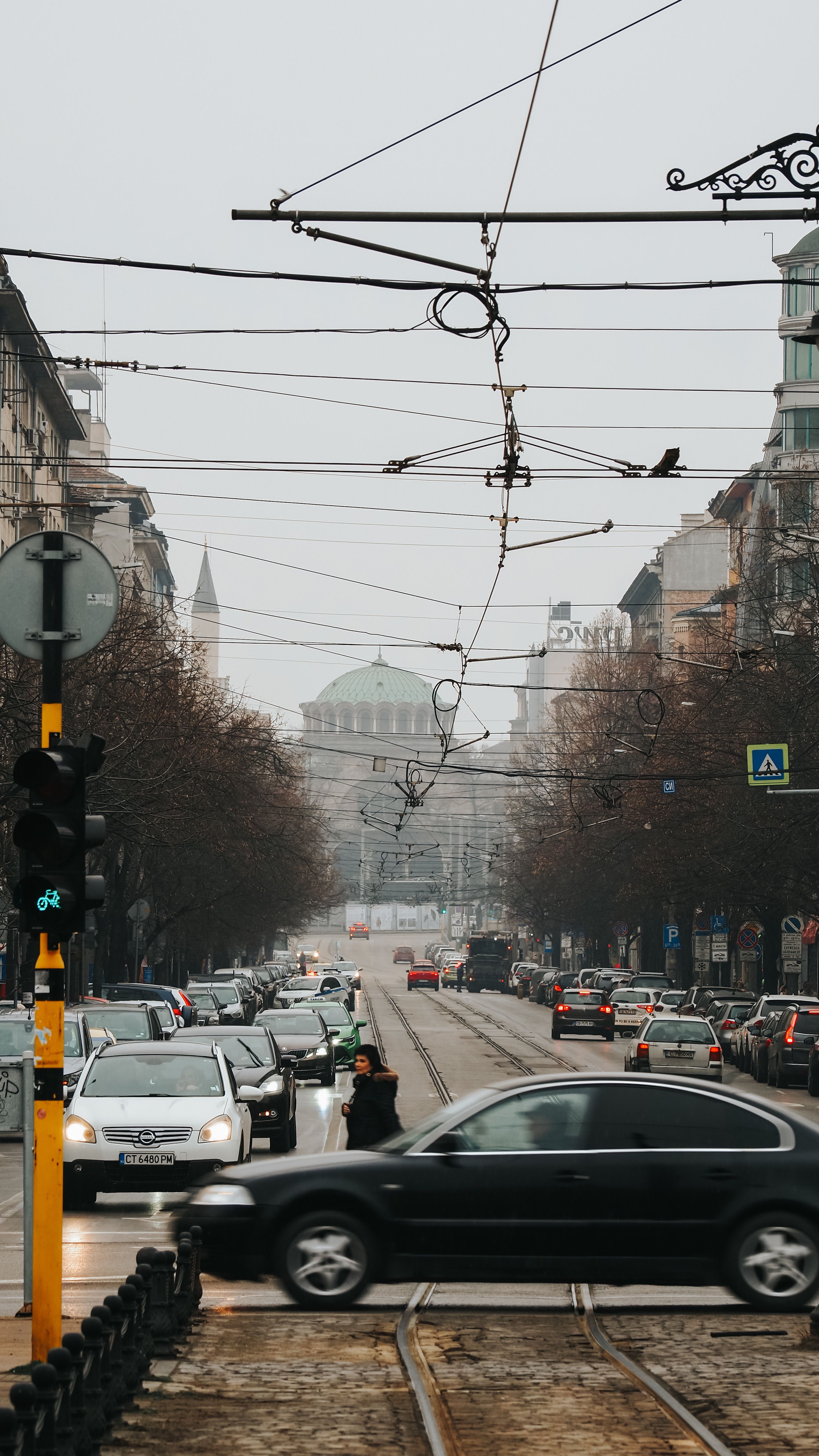 Dynamic view of a bustling street in Sofia with traffic and landmark in the distance.