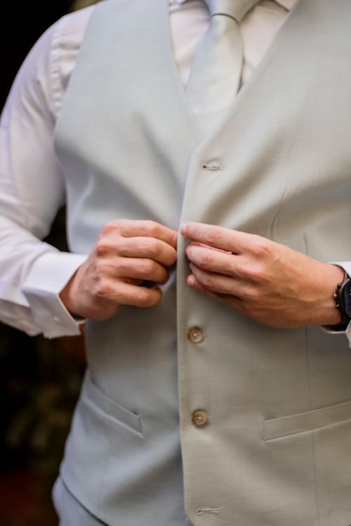Free Man buttoning a light gray vest over a white shirt, emphasizing formal fashion. Stock Photo