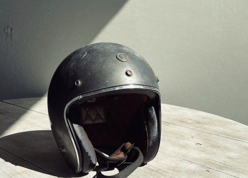 Casque moto vintage ouvert de type jet, posé sur un tabouret en bois