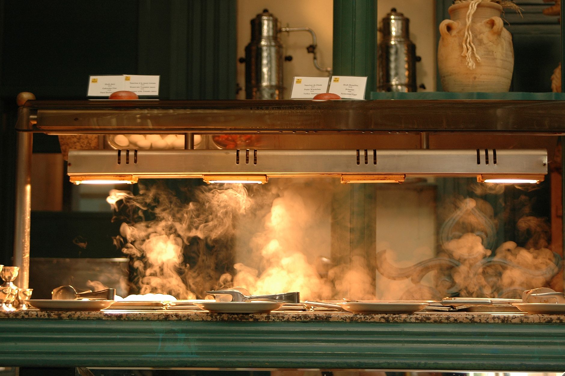 Buffet counter with steaming dishes under warm lighting, creating a cozy culinary atmosphere.
