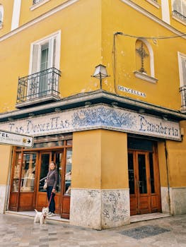 A historic yellow building in Seville, Spain with a bread shop facade and street details.