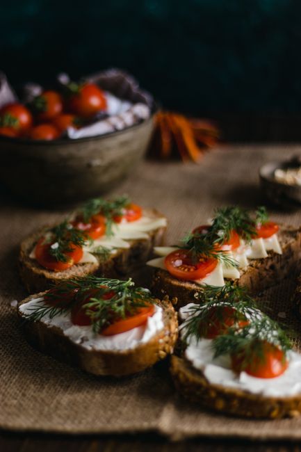 Artistic display of multi-grain bread topped with cherry tomatoes and herbs, perfect for food lovers.