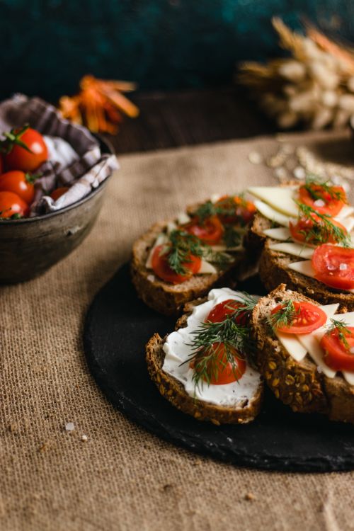 Free Delicious multigrain bread topped with feta cheese, tomatoes, and herbs on burlap background. Stock Photo