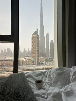Scenic view of Burj Khalifa from a modern bedroom window with a cup of coffee.