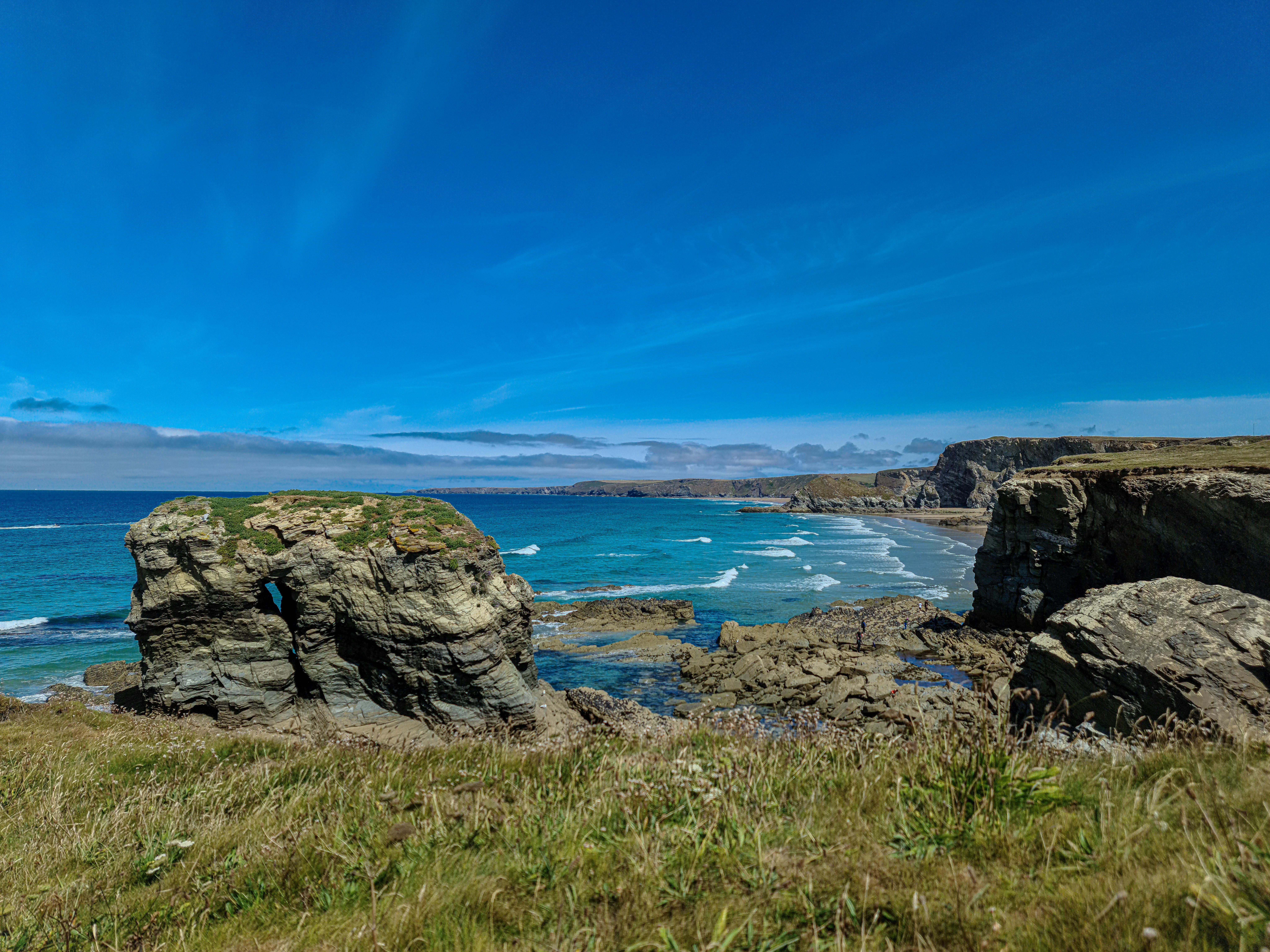 Explore the stunning coastal cliffs and azure sea in Newquay, England under a vivid blue sky.