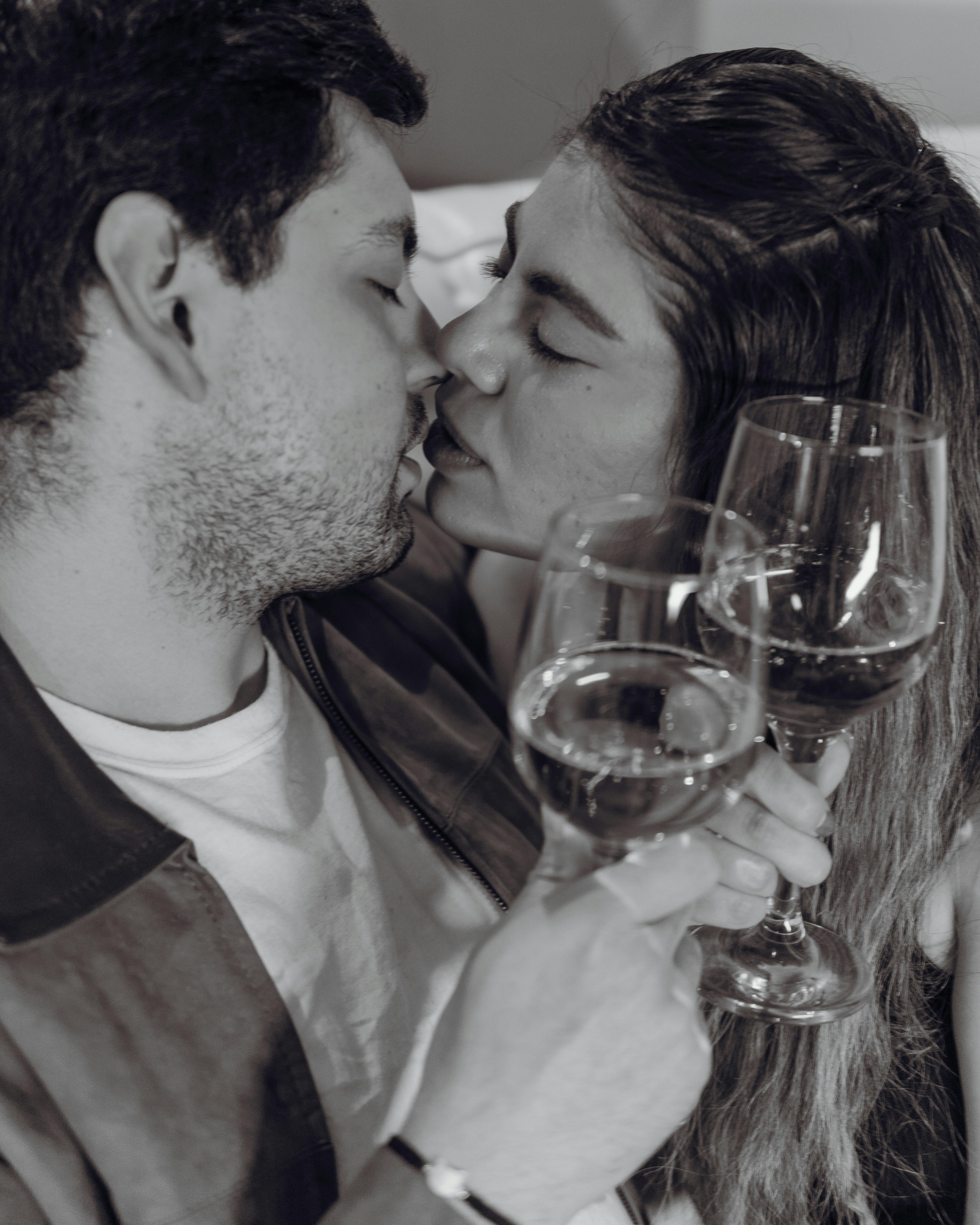 romantic couple sharing a kiss with wine glasses