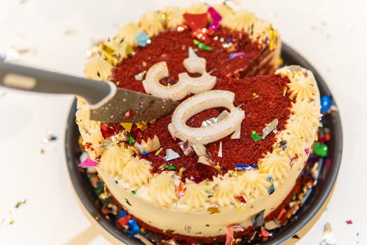Vibrant red velvet cake with cream frosting and colorful candles, perfect for a birthday celebration.
