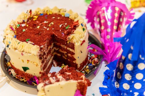 Free Red velvet cake surrounded by colorful party hats and confetti, ideal for celebrations. Stock Photo