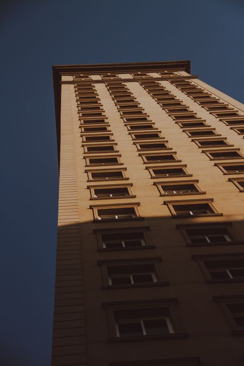Free Low-angle view of a tall building against a deep blue sky, showcasing urban architecture. Stock Photo