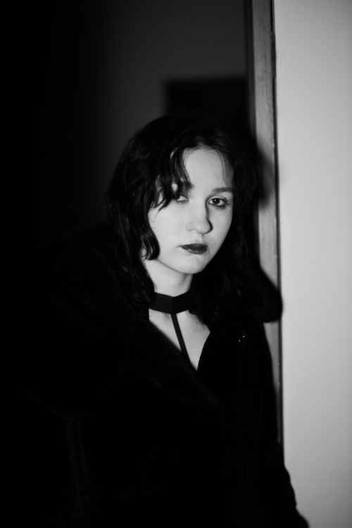 Free Moody black and white portrait of a woman by a doorway, creating a dramatic atmosphere. Stock Photo