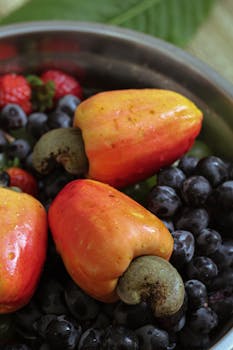 A vibrant display of fresh cashew apples, grapes, and strawberries for healthy eating.