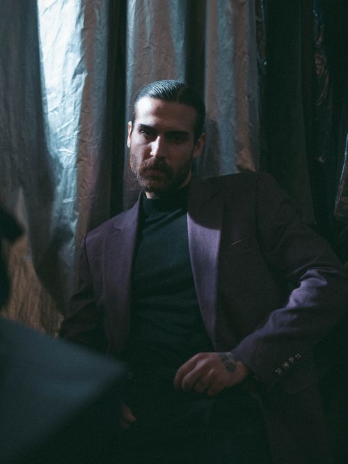 Free A dramatic portrait of a man in a suit sitting in low light with a contemplative expression. Stock Photo
