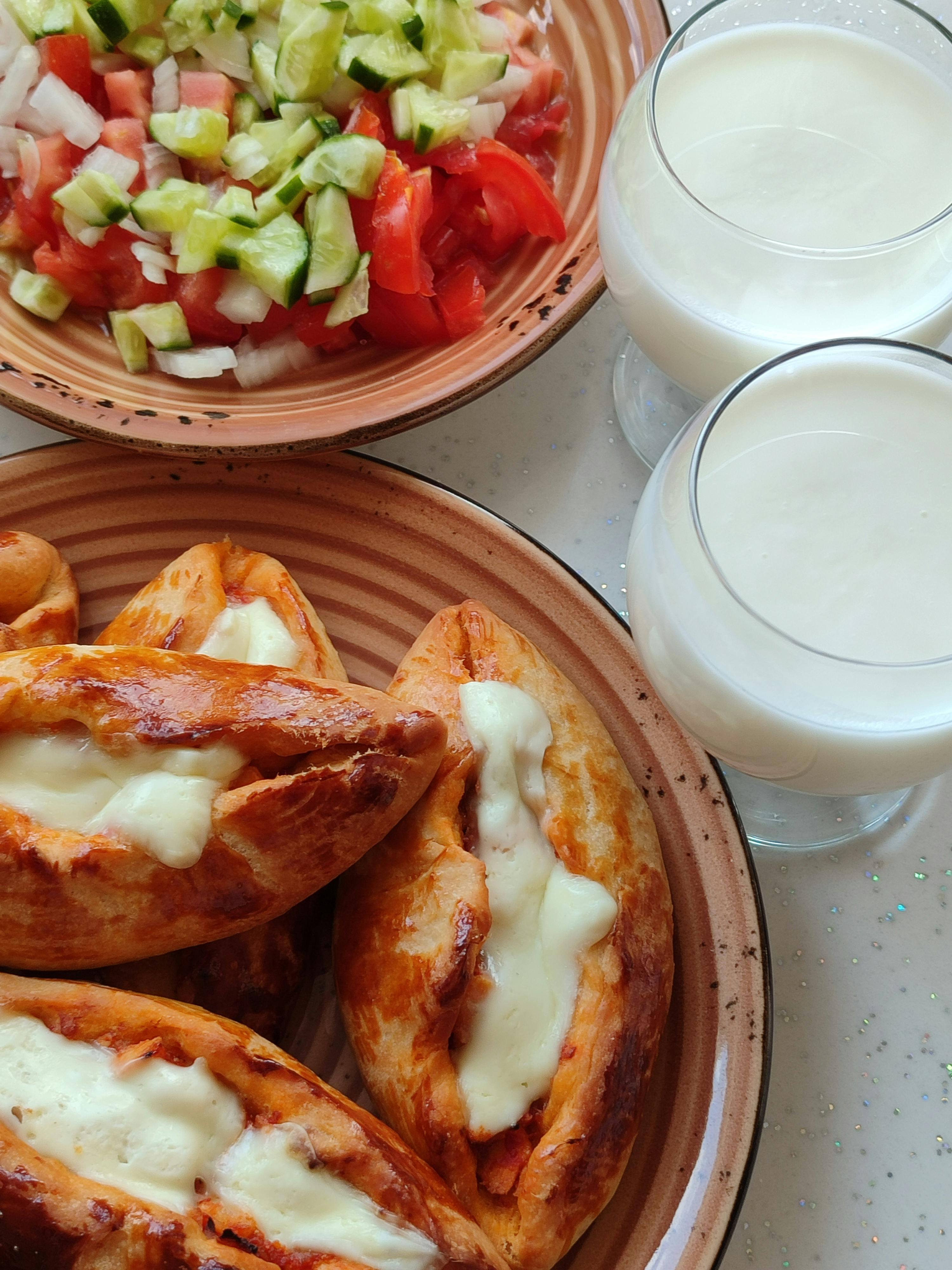 Golden-brown Turkish köfte burger nestled in warm pide bread, generously topped with creamy yogurt-herb sauce, fresh tomatoes, red onion, and crisp lettuce