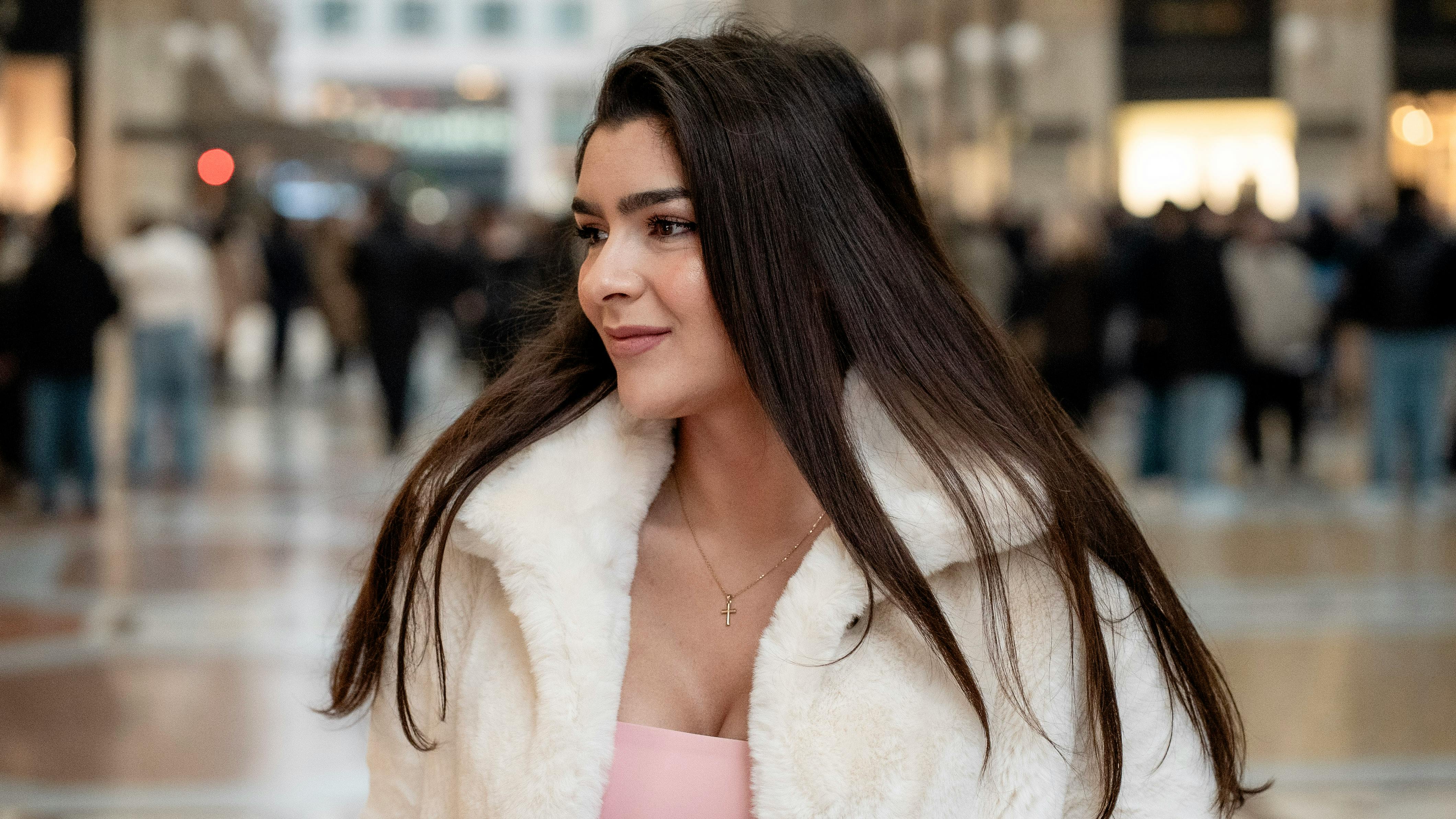 Stylish woman in white coat poses in Milan's iconic shopping gallery.