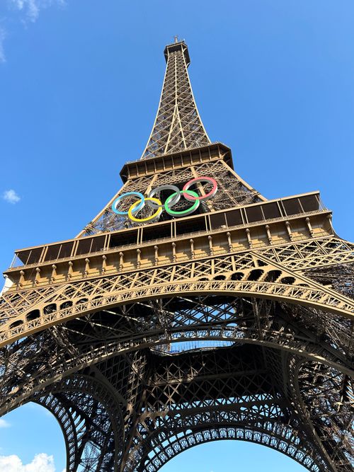 Free Iconic Eiffel Tower in Paris adorned with vibrant Olympic Rings against a clear blue sky. Stock Photo