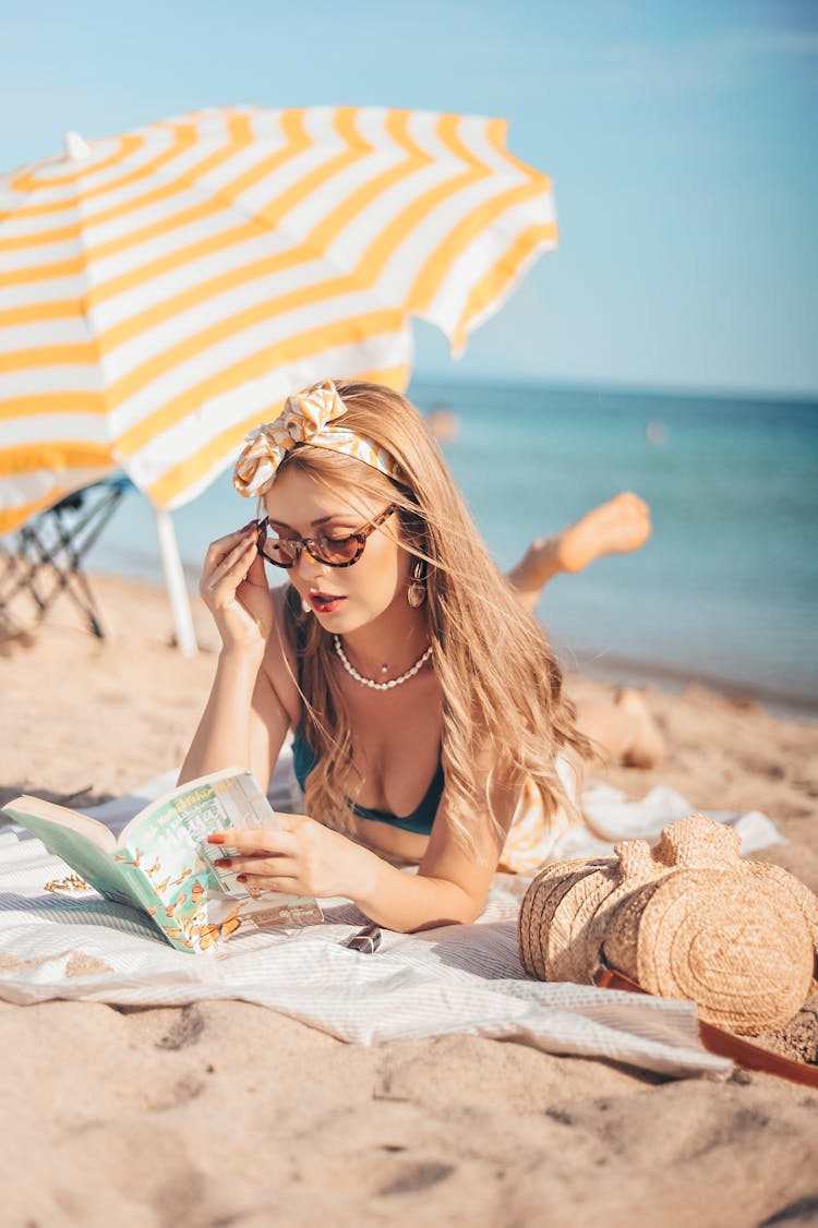 Women's Lying On The Beach Sand Reading A Book
