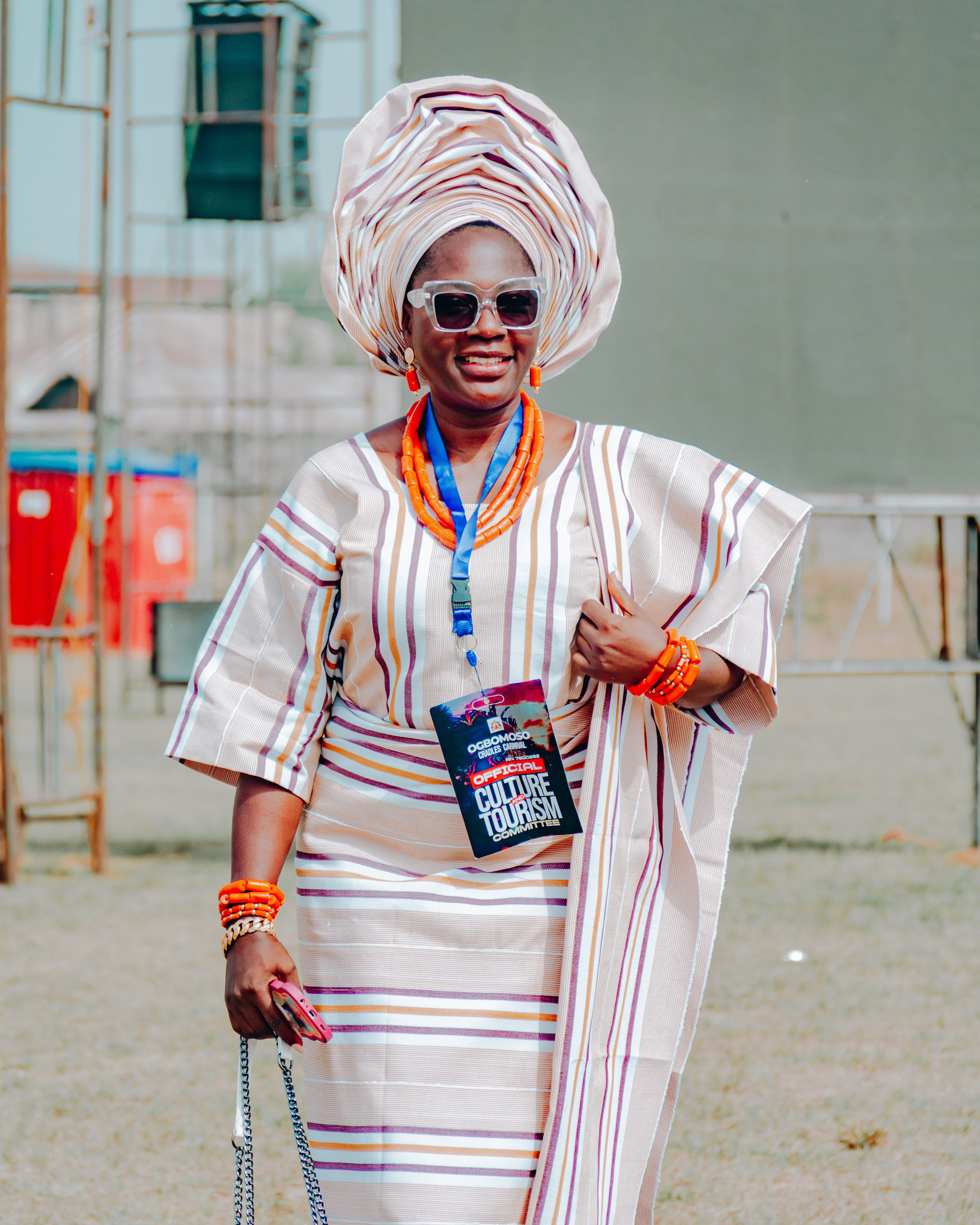 A woman in traditional Nigerian dress, showcasing cultural heritage and vibrant fashion outdoors.