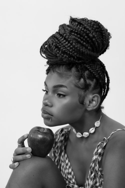 Free Artistic black and white portrait of a young woman holding an apple, expressing contemplation. Stock Photo