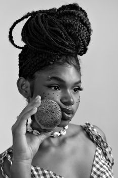 Creative black and white portrait of a woman holding a fruit with artistic makeup.