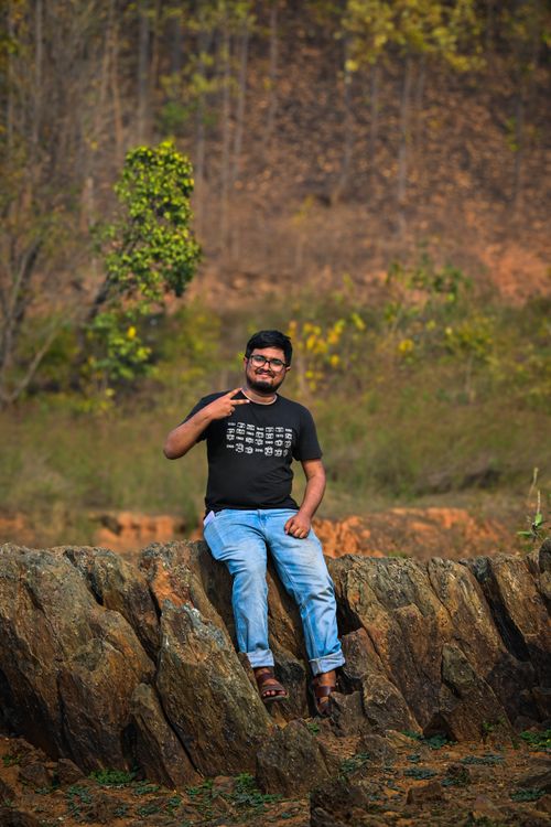 Free A cheerful man posing on a rock formation in the natural landscape of Kolkata, India. Stock Photo