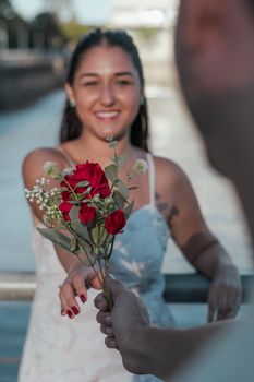A woman receives a bouquet of red roses by the waterfront in Buenos Aires, Argentina.