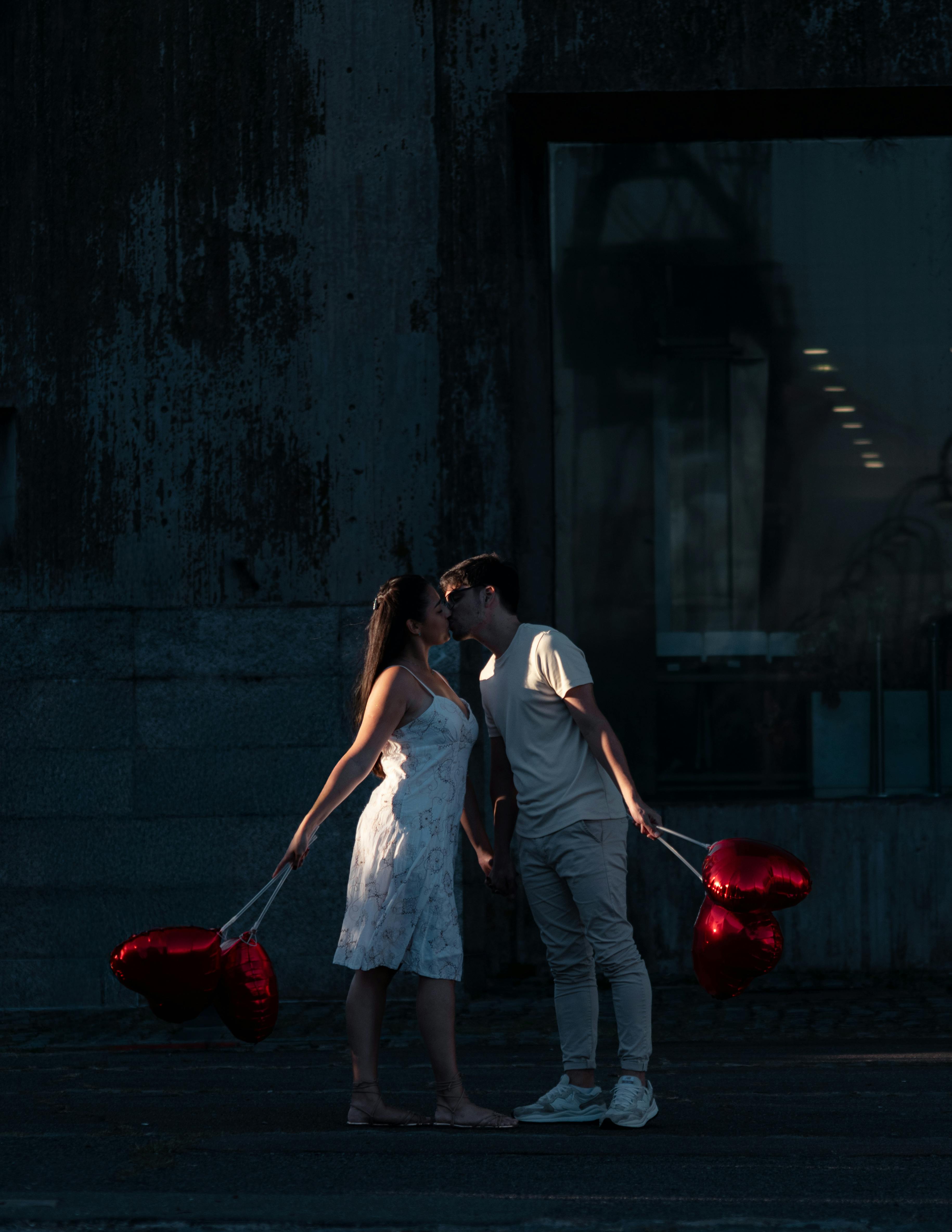 Couple kissing on a street holding heart-shaped balloons in Buenos Aires.