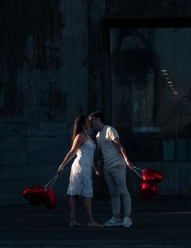 Couple kissing on a street holding heart-shaped balloons in Buenos Aires.