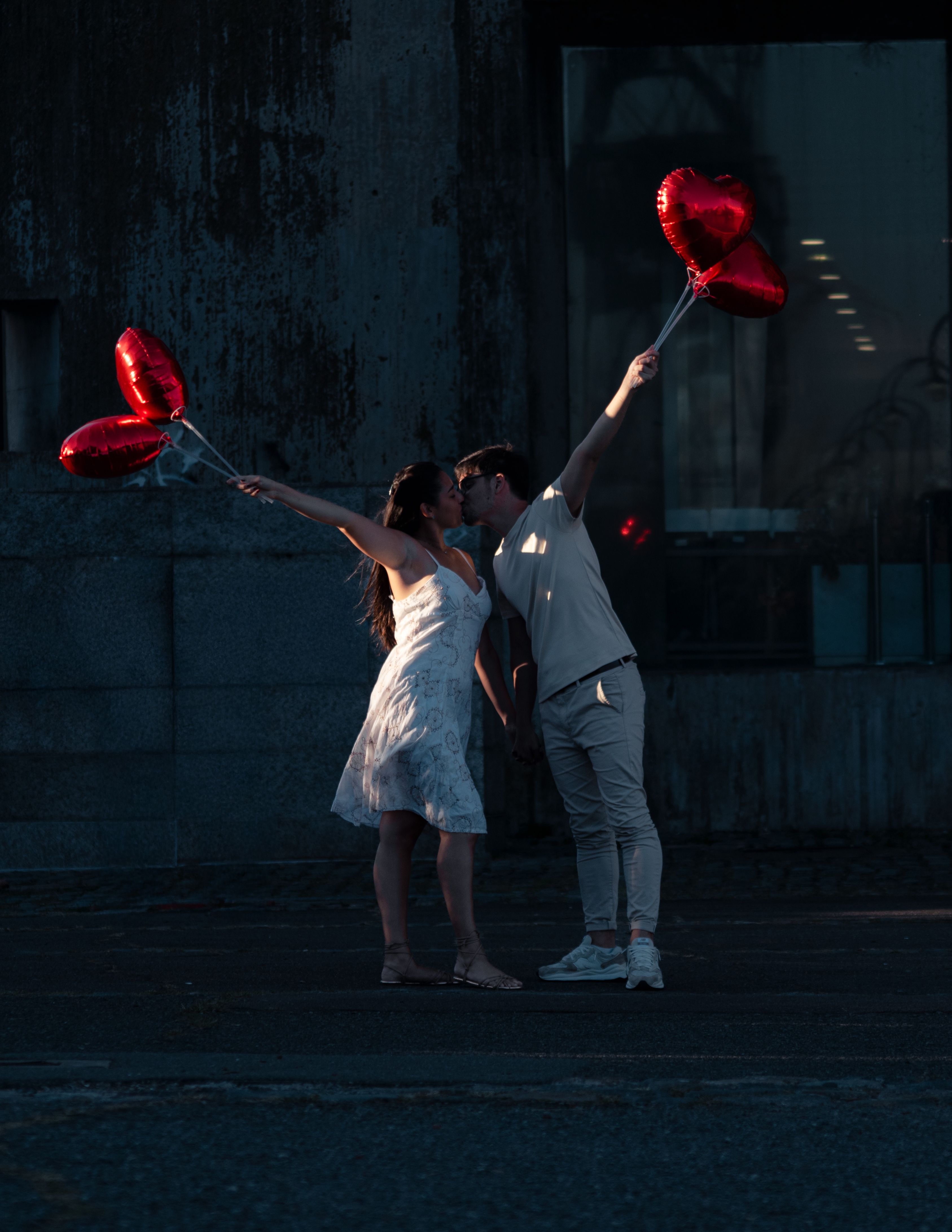 A couple sharing a romantic moment with heart-shaped balloons in Buenos Aires at sunset.