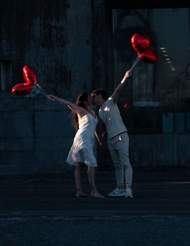 A couple sharing a romantic moment with heart-shaped balloons in Buenos Aires at sunset.