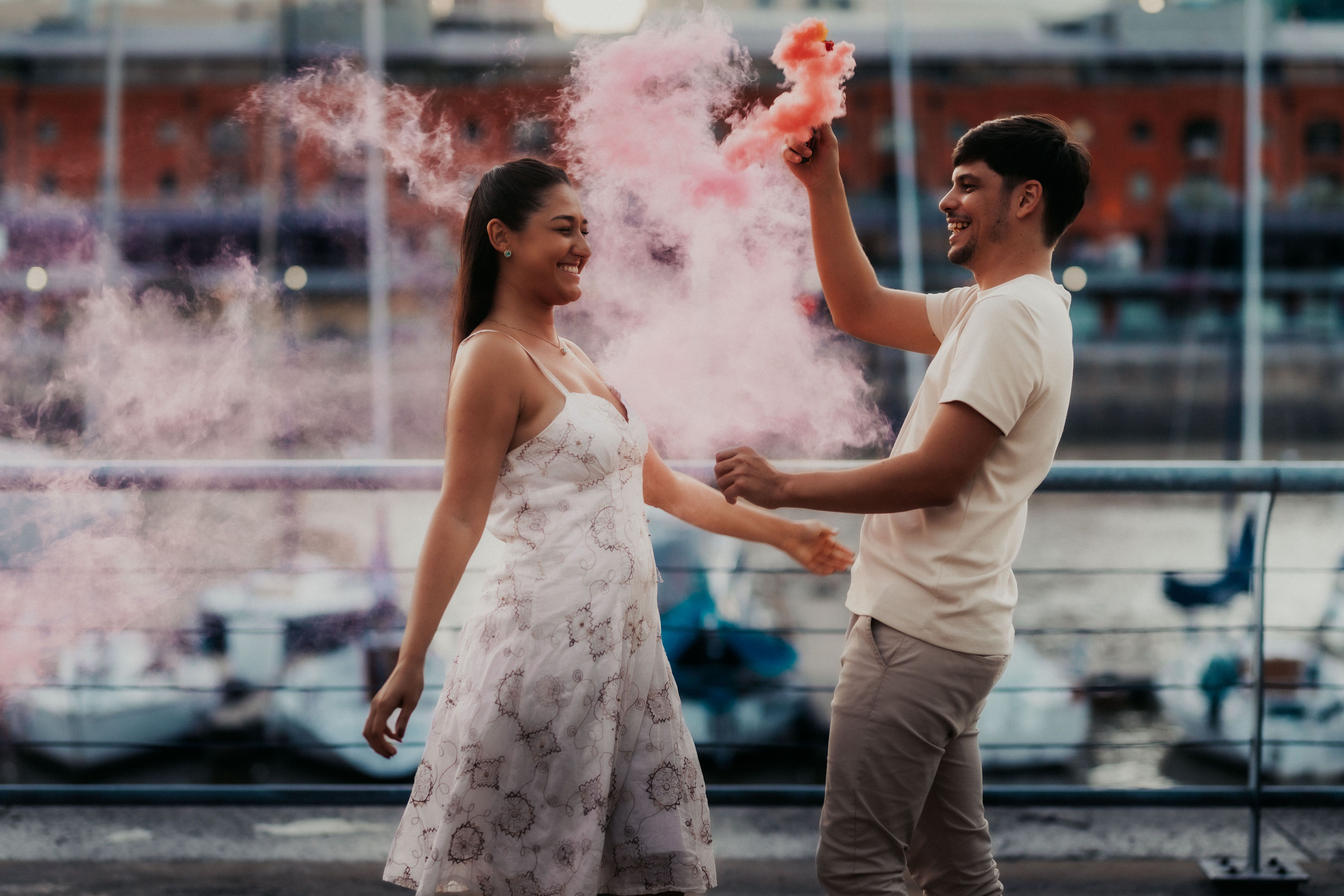 Young couple enjoying a vibrant celebration with pink smoke in Buenos Aires. Lively and joyful atmosphere captured.
