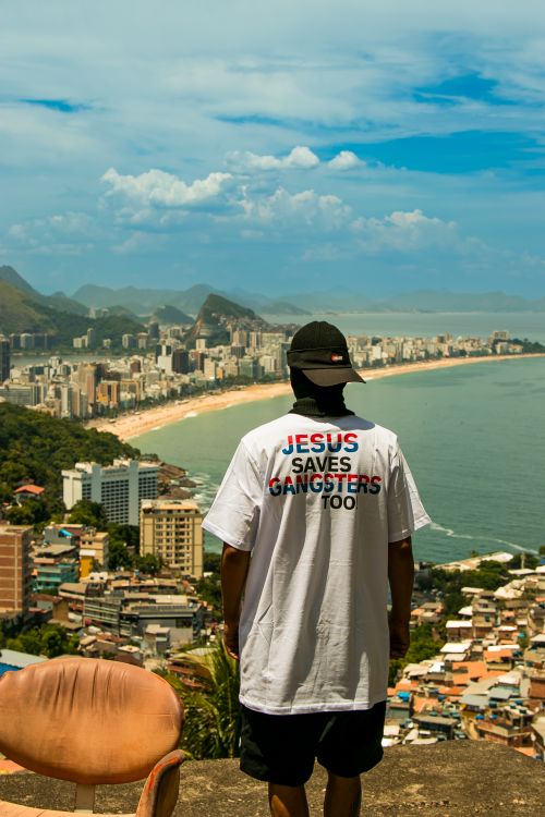 Free Person overlooks Rio de Janeiro wearing a 'Jesus Saves Gangsters Too' shirt. Stock Photo