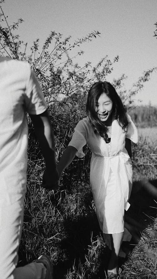 Free Black and white cheerful ethnic female holding hand with boyfriend and following crop man on summer day in nature Stock Photo