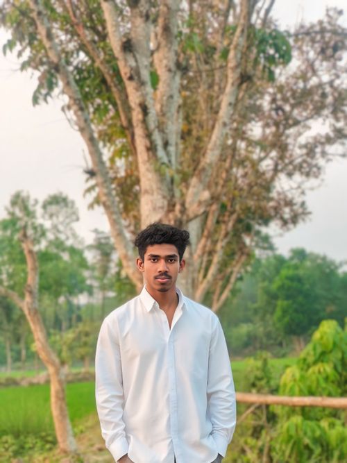 Free Portrait of a young man in a serene outdoor setting with lush greenery. Stock Photo