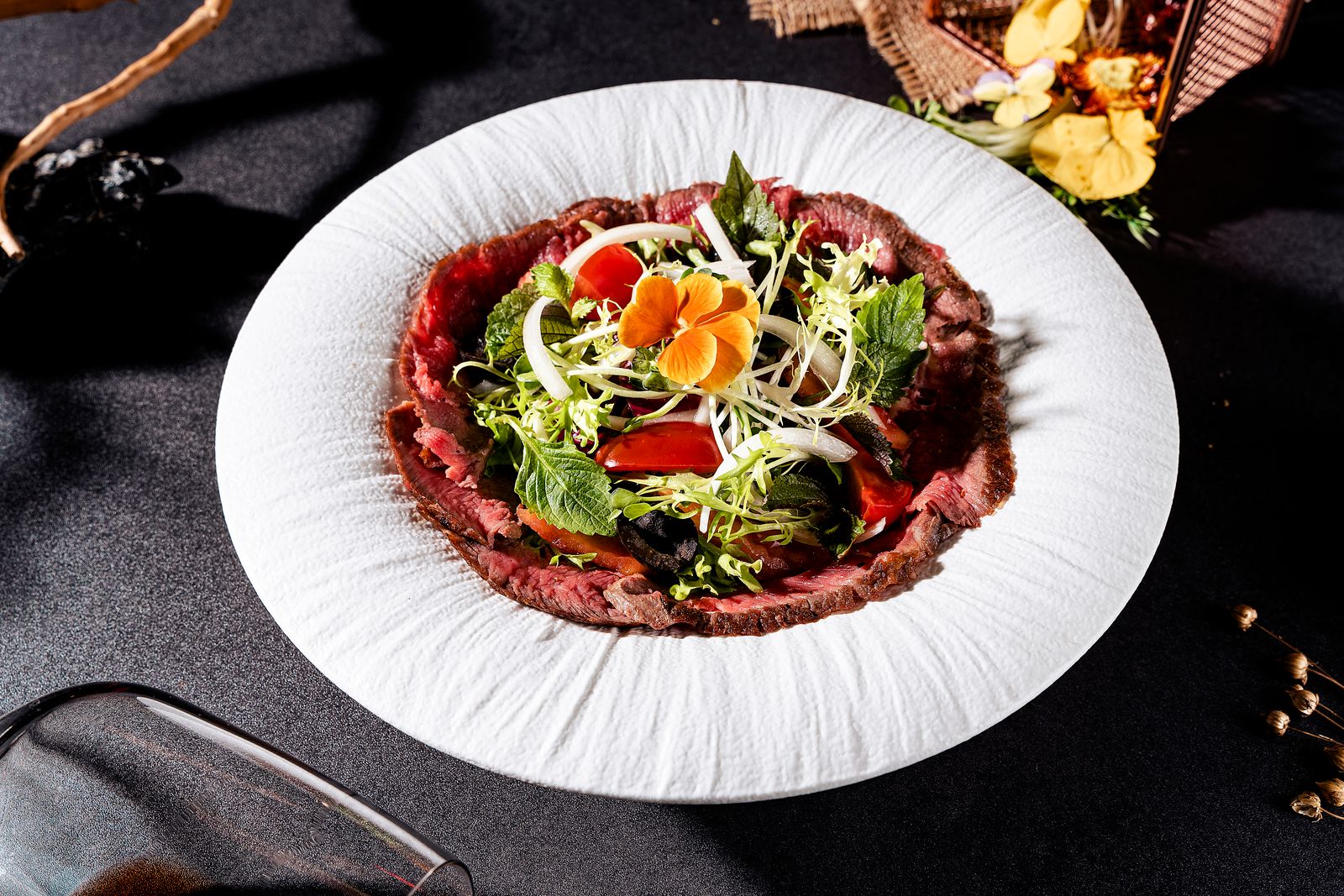 Elegant opgemaakte rundercarpaccio met rucola, Parmezaan en garnituur.