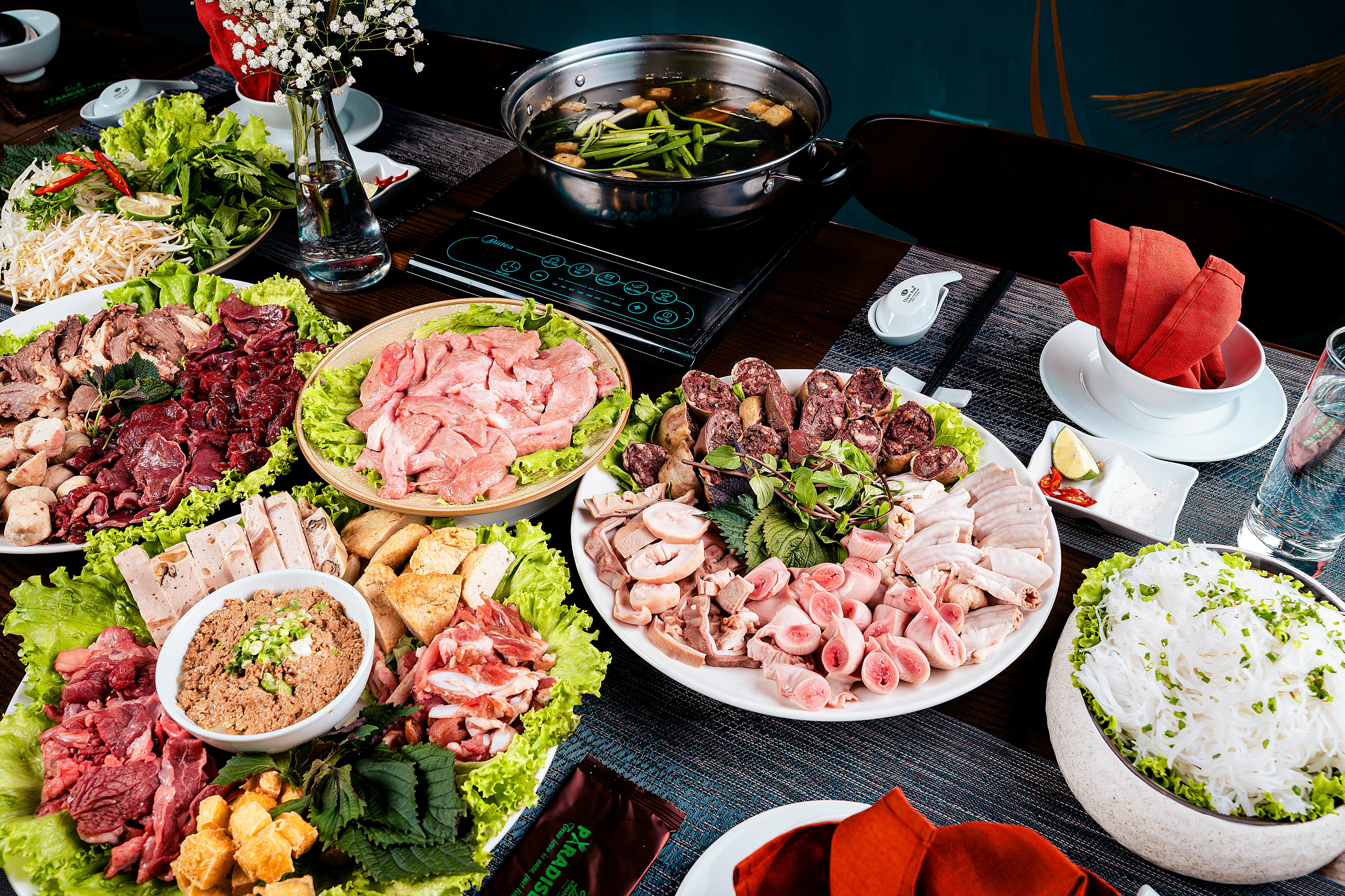 A vibrant display of ingredients for a traditional Vietnamese hot pot meal, showcasing fresh meats and vegetables.