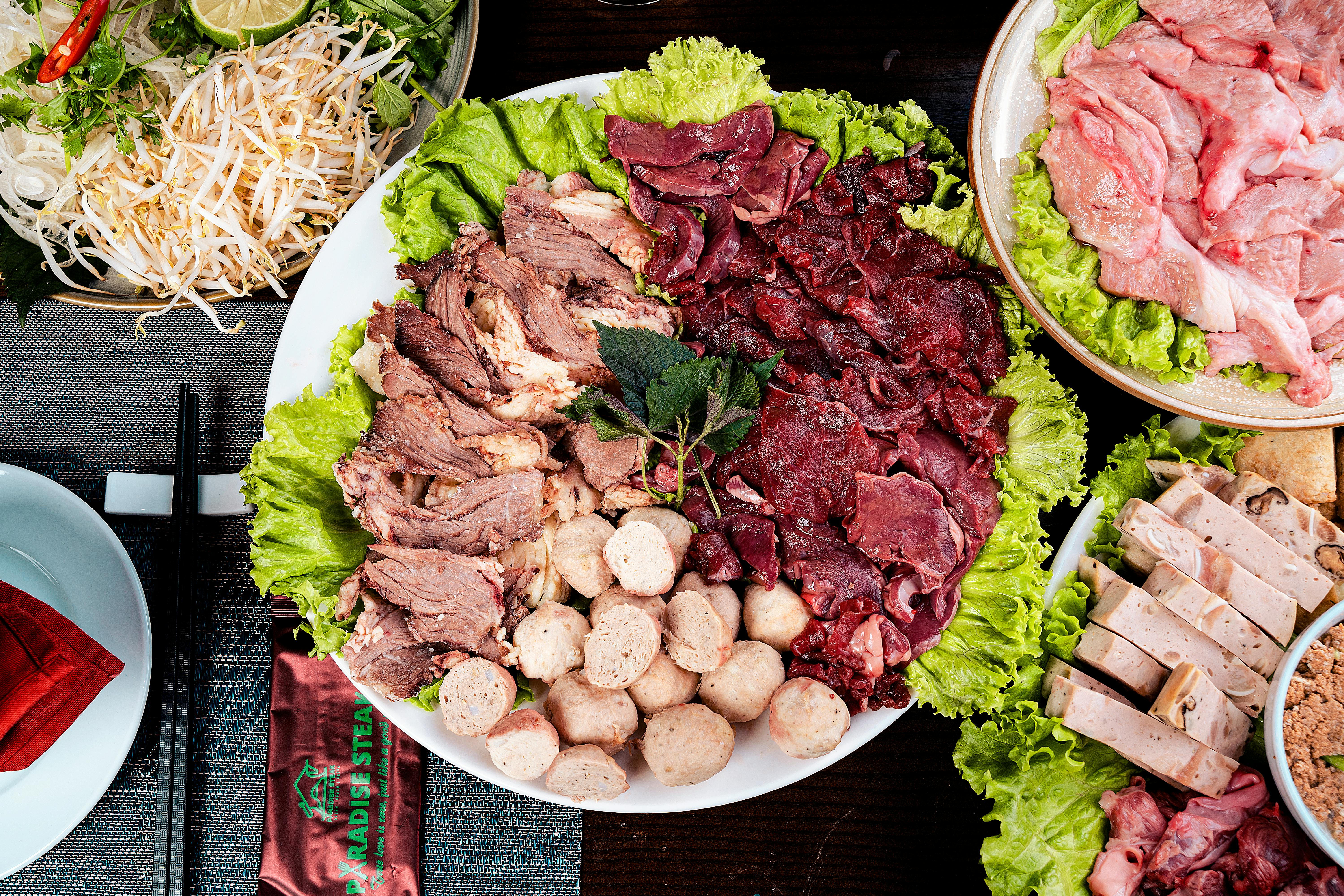 Top view of a Vietnamese hot pot featuring assorted meats with fresh vegetables, perfect for a communal meal.