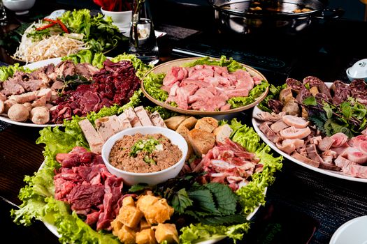 A vibrant assortment of meats and vegetables prepared for a traditional Asian hotpot meal.