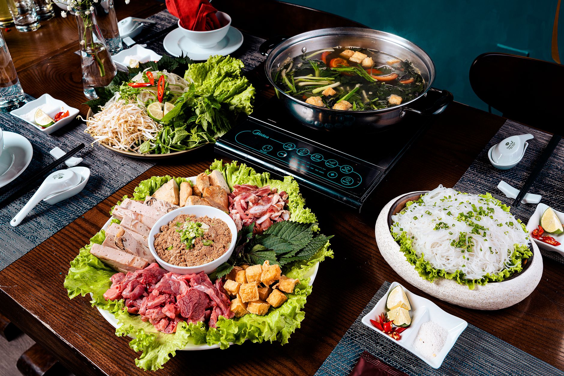 A vibrant spread of Vietnamese hot pot ingredients with fresh vegetables, meats, and noodles.