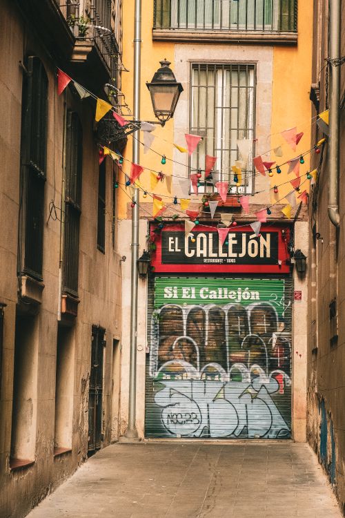Free Vibrant alley featuring graffiti and colorful banners in an urban setting. Stock Photo