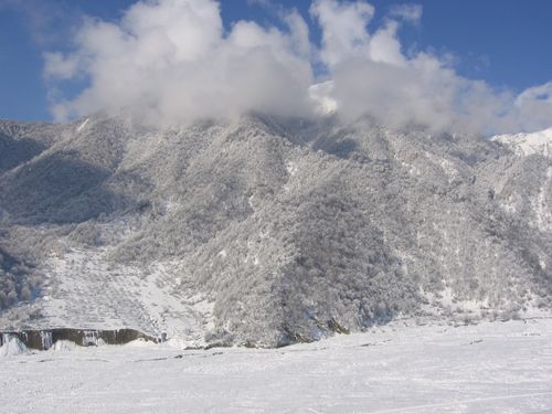 Free Stunning view of a snow-covered mountain with clouds and blue sky. Stock Photo