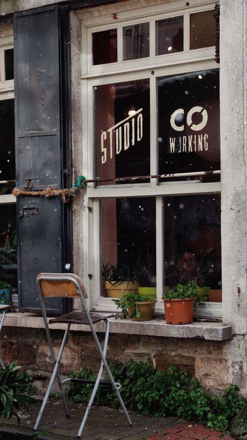 Free Street view of a stylish studio coworking space with exterior plants and chair setup. Stock Photo