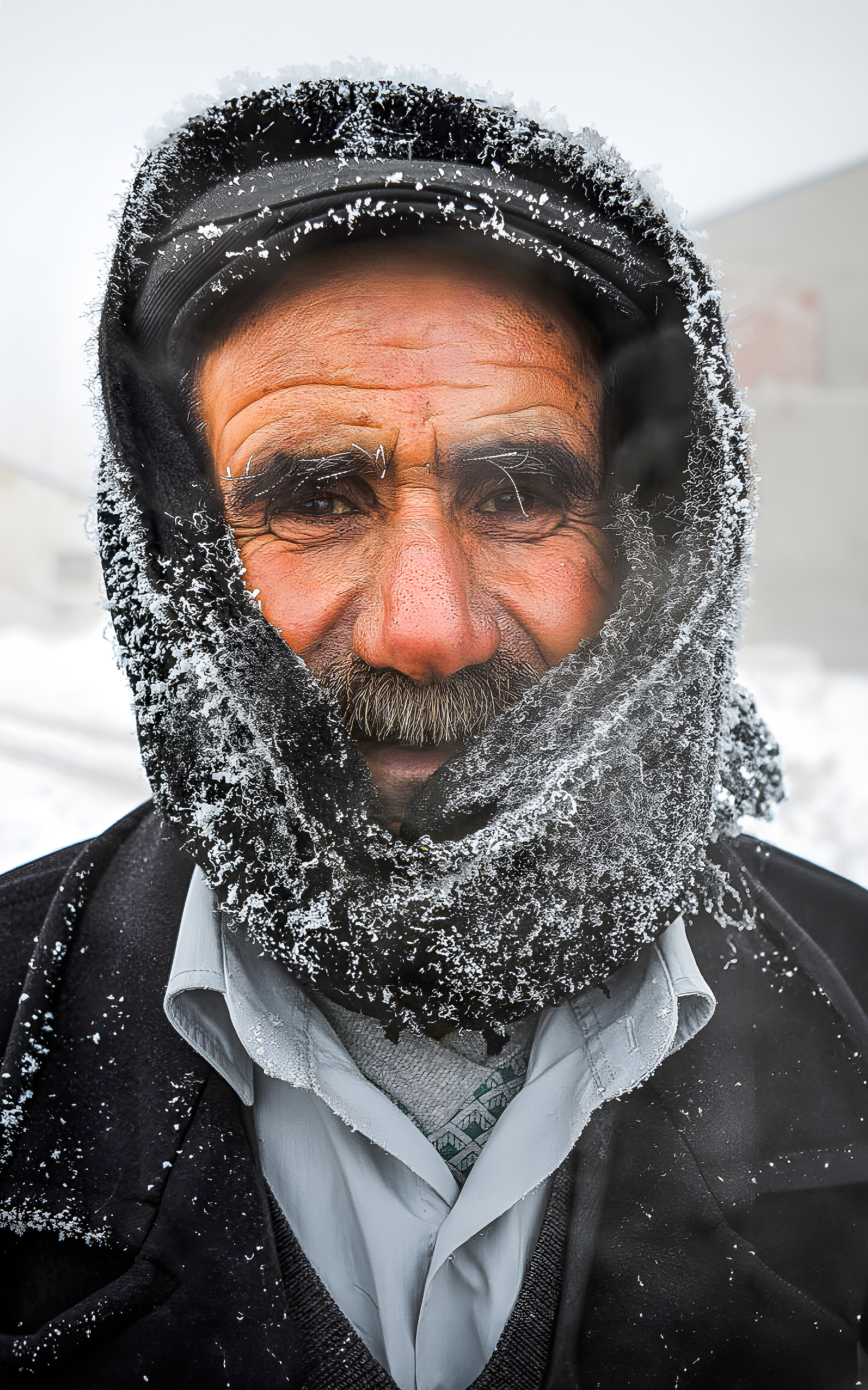 Portrait of a warmly dressed elderly man covered in frost and snow in snowy Ağrı, Türkiye.