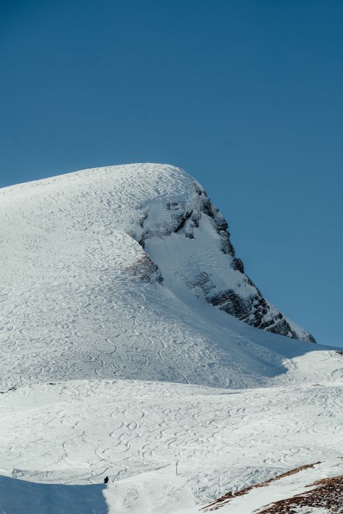 Free A serene snow-covered mountain under a clear blue sky, showcasing untouched snowy terrain. Stock Photo