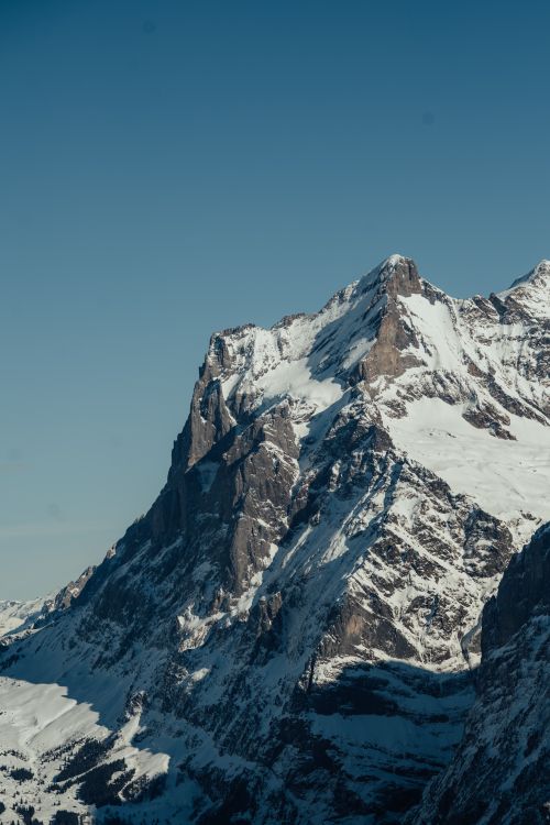 Free Breathtaking view of a towering snow-capped mountain under a clear blue sky. Stock Photo