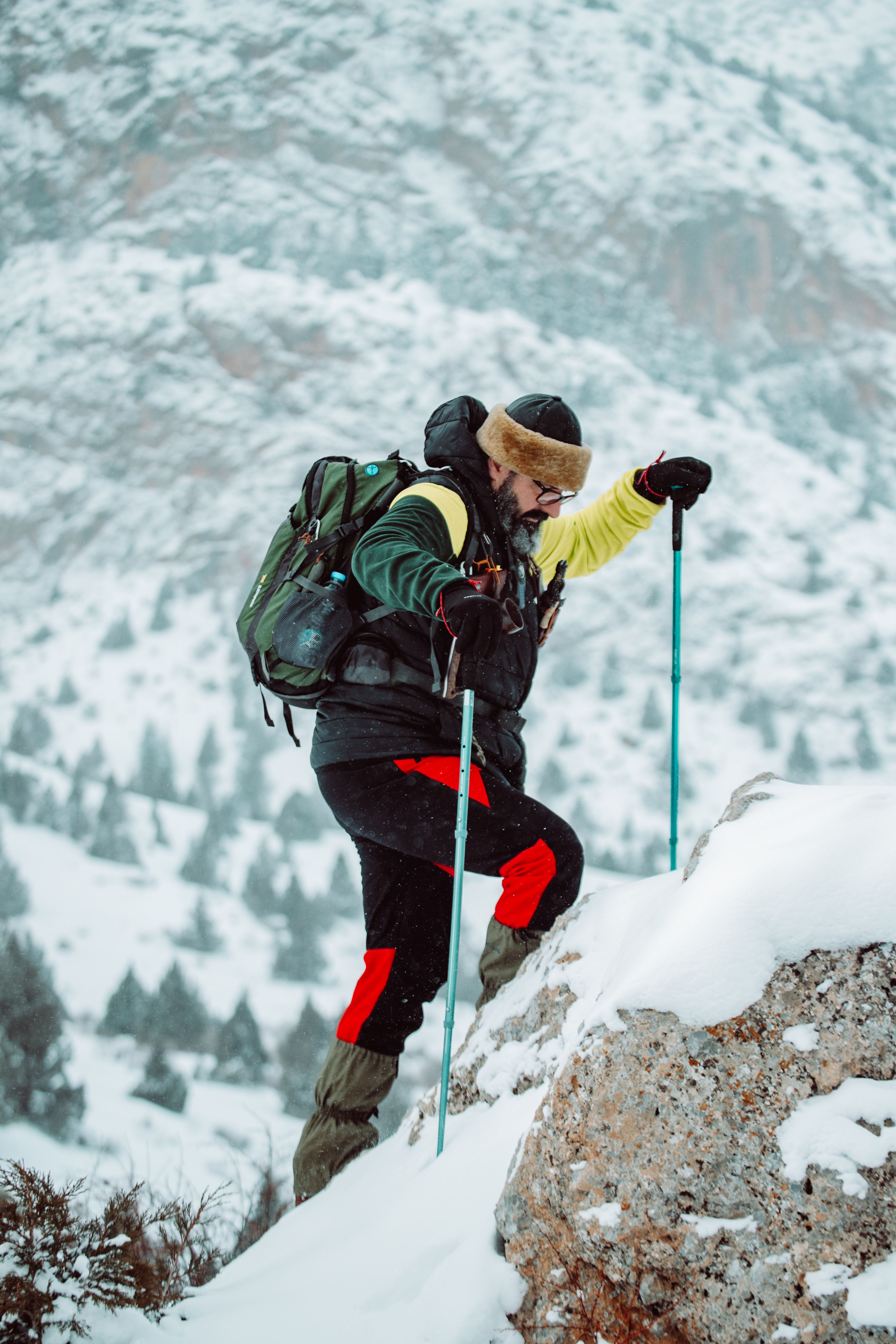 Mountaineer climbing a steep snowy slope in full cold-weather gear, the conditions a Kilimanjaro packing list has to prepare you for near the summit