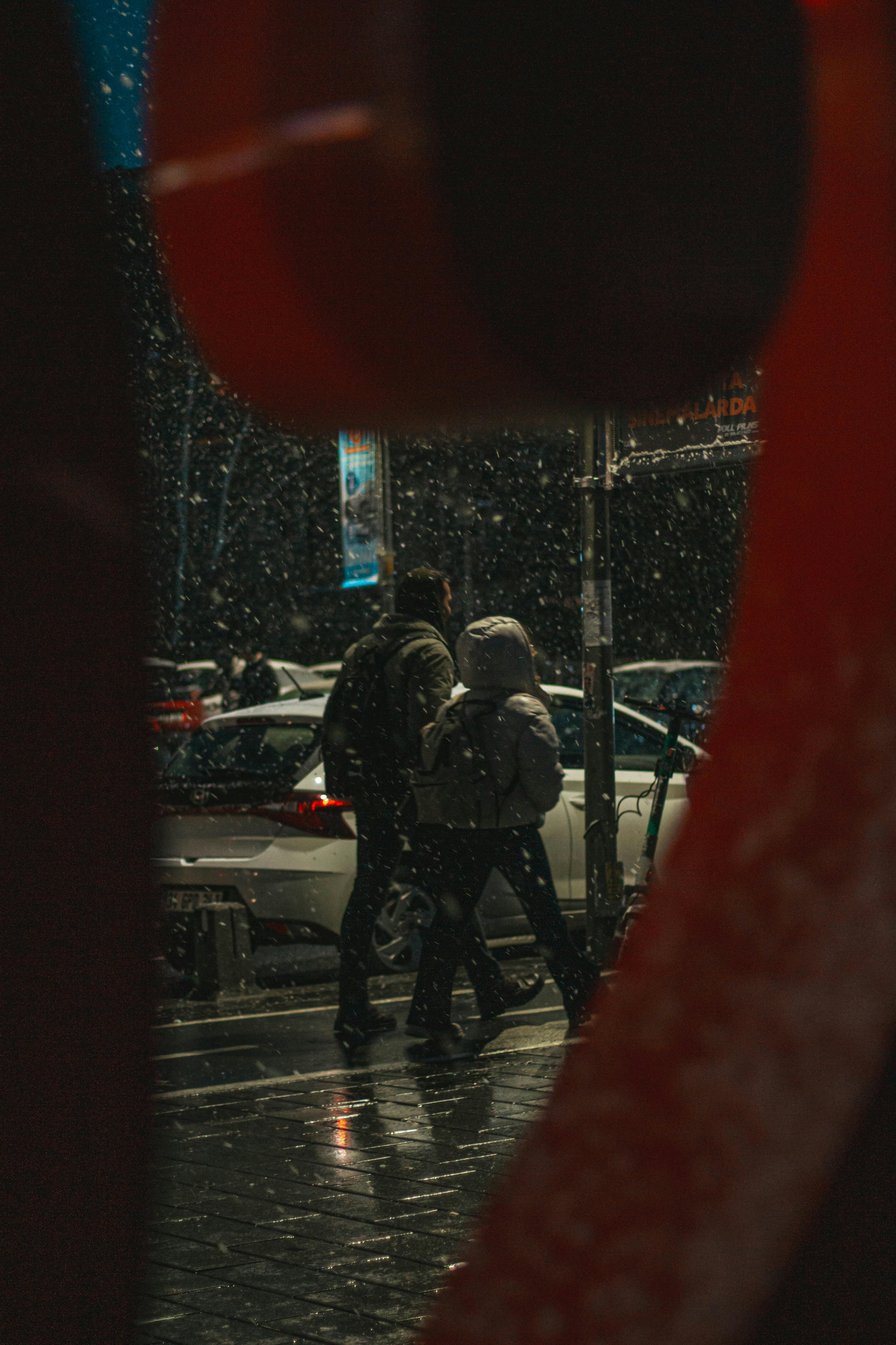 Gratuit Couple marchant dans les rues enneigées d'Istanbul la nuit, capturé dans une scène urbaine de mauvaise humeur. Photos