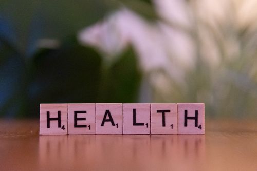 Free Close-up of Scrabble tiles spelling 'Health' on a wooden table with a blurred background. Stock Photo